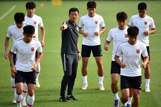 球队在训练场进行战术演练，教练在场边指导球员